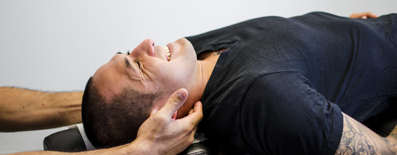 Doctor adjusting patient's neck while smiling.