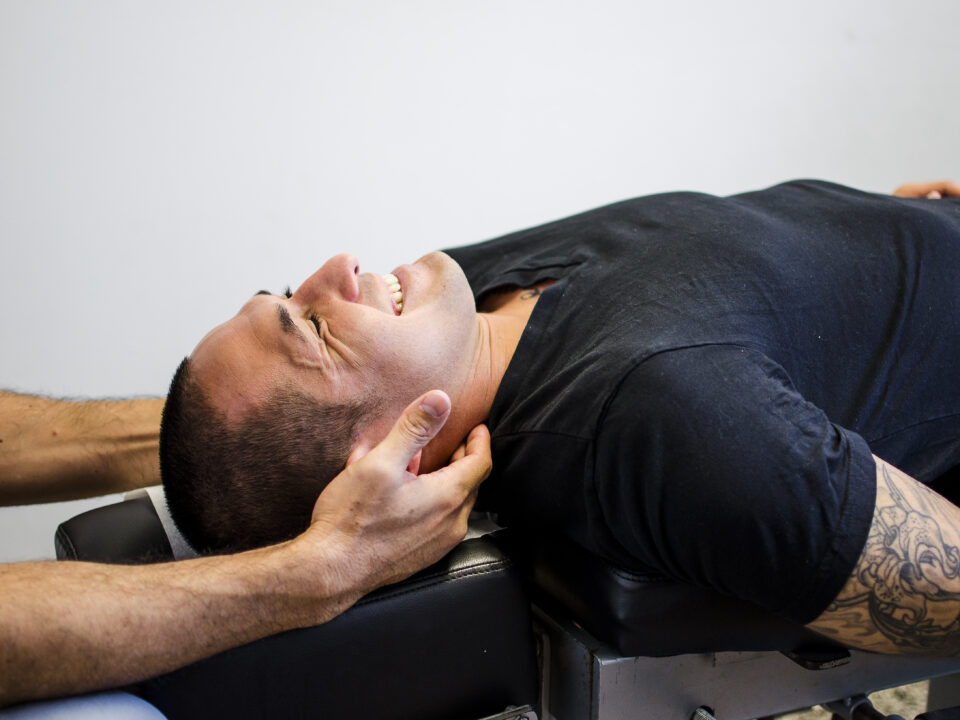 Doctor adjusting patient's neck while smiling.