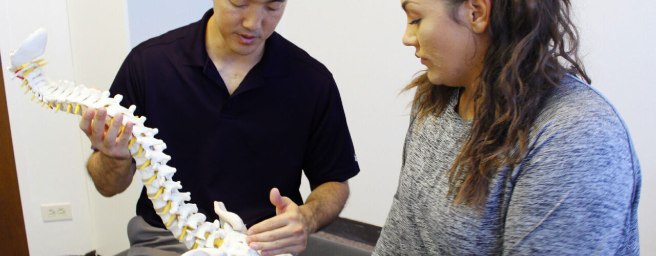 Dr. Shaun Ohira, with spine, speaking to the patient.