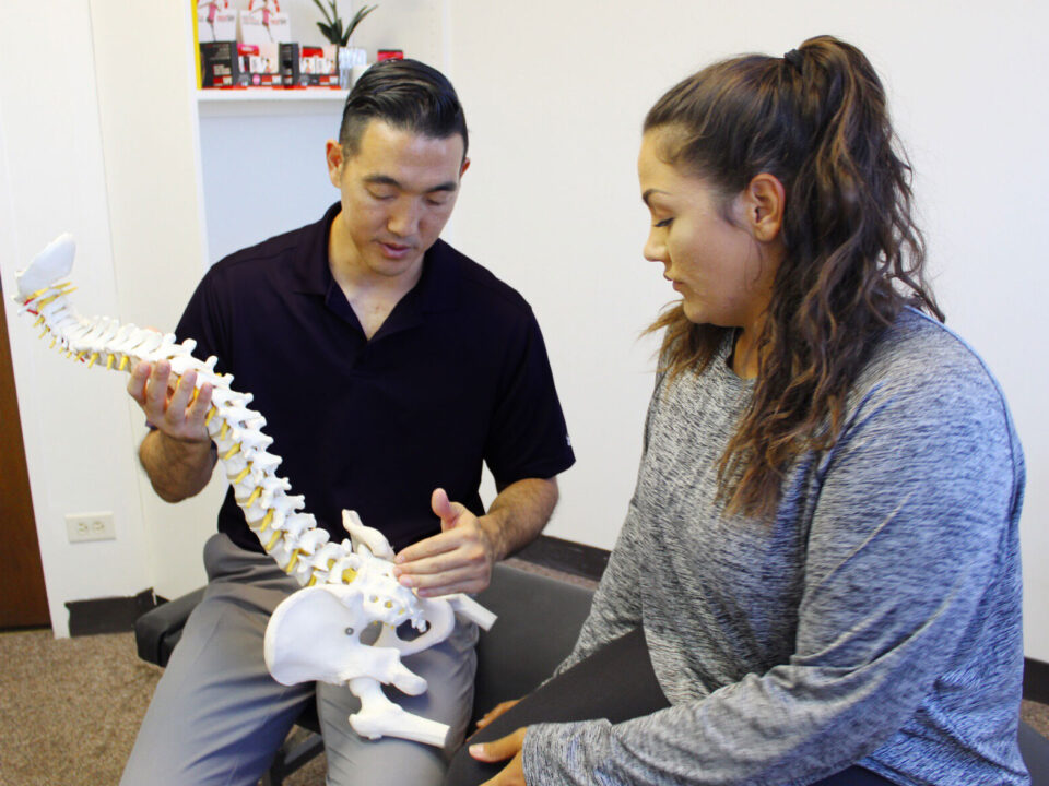 Dr. Shaun Ohira, with spine, speaking to the patient.