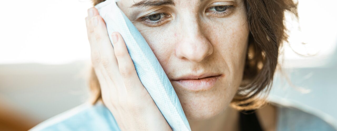A lady holding an ice pack to her jaw