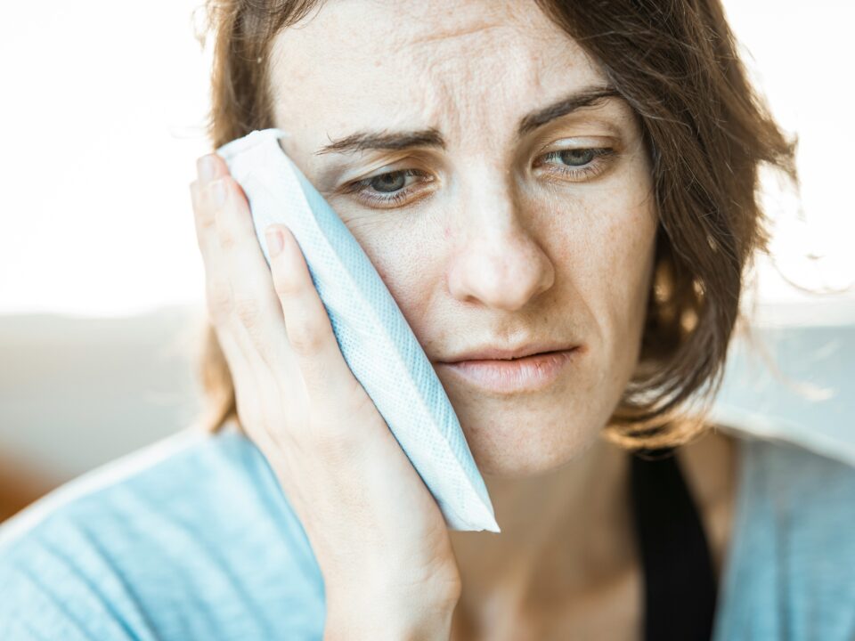 A lady holding an ice pack to her jaw