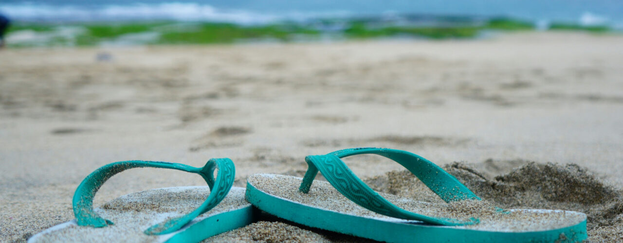 A pair of flip flops sitting in the sand.