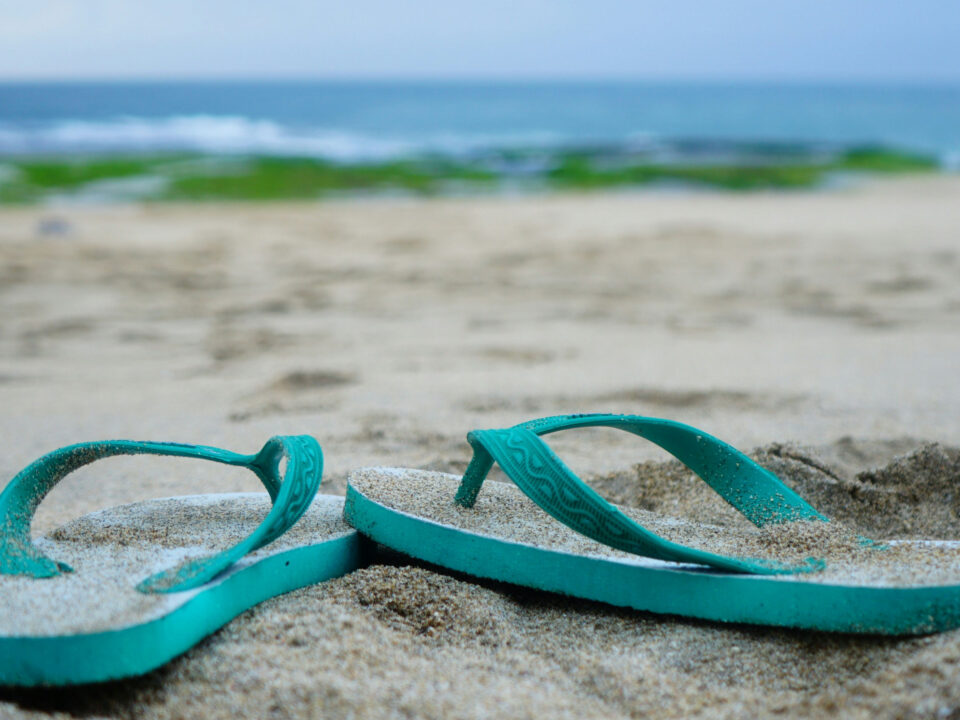 A pair of flip flops sitting in the sand.