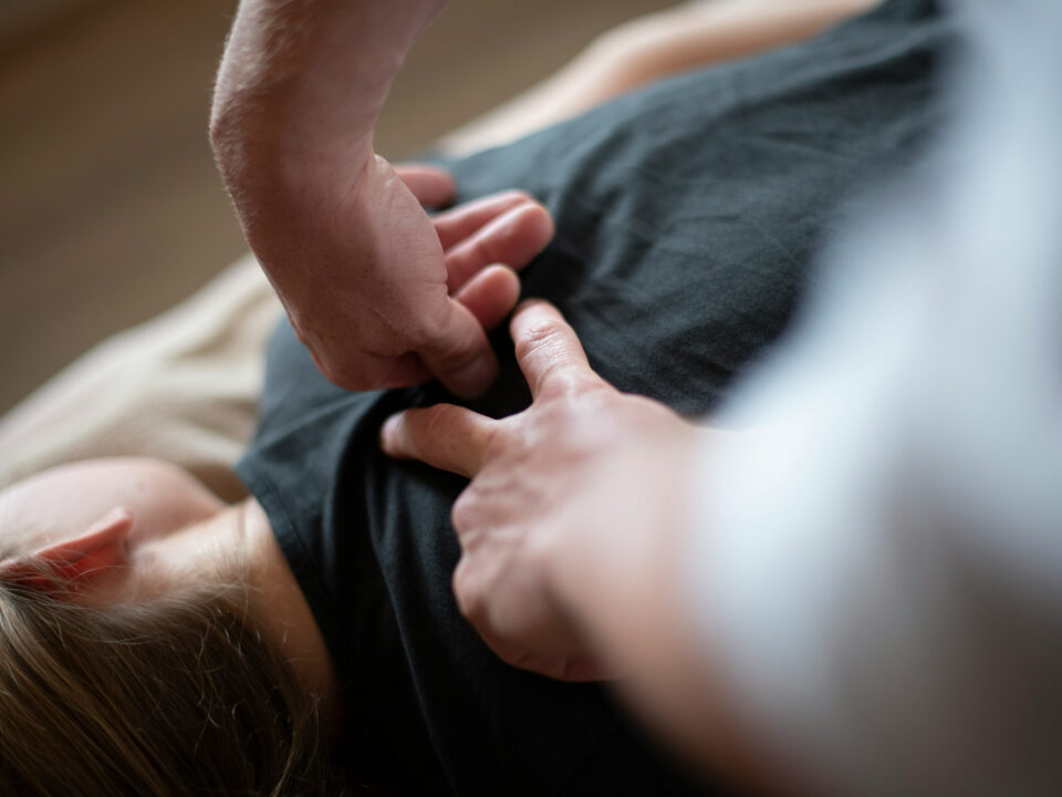 A chiropractor putting pressure into a woman's shoulder blade