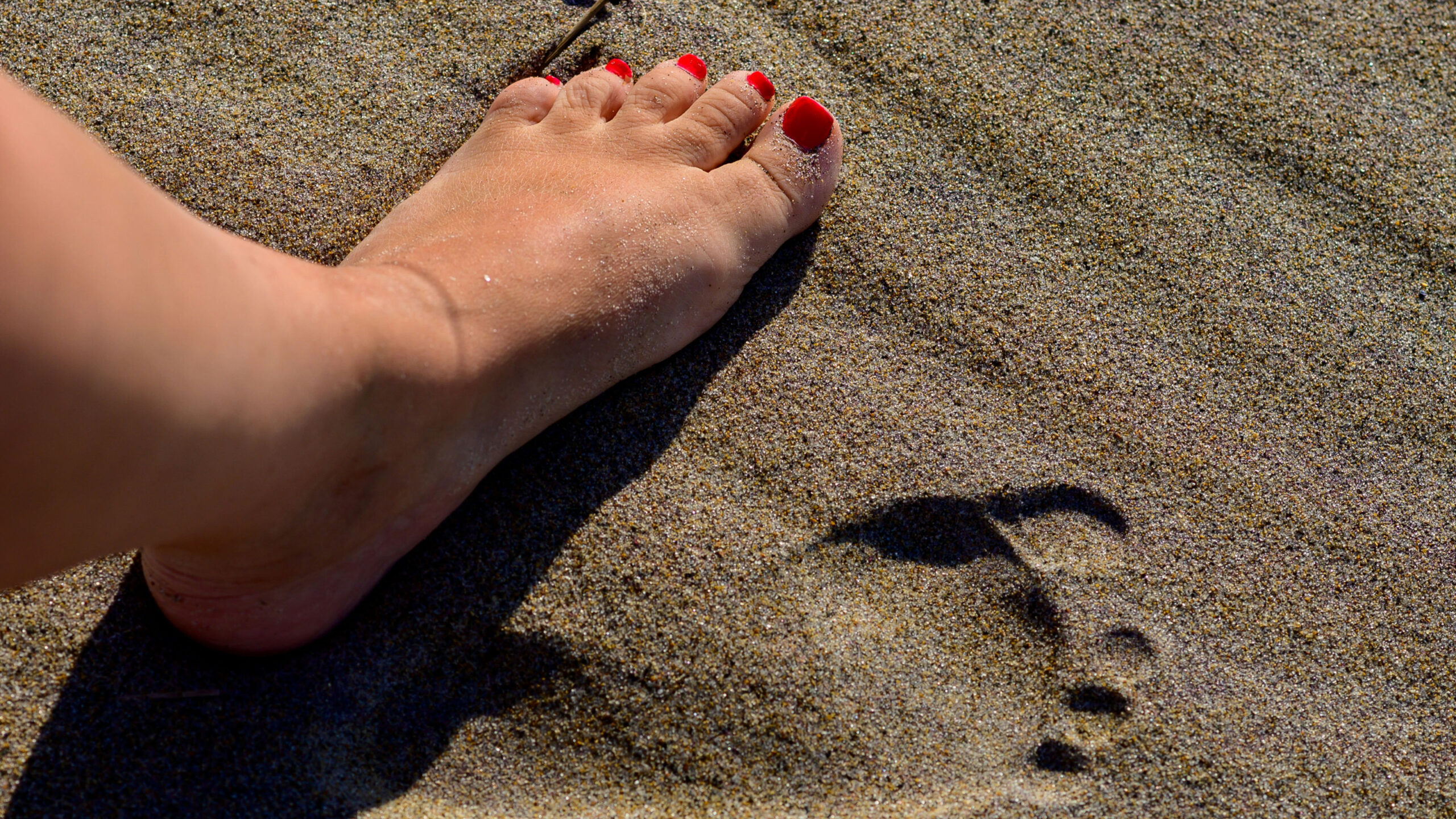 A lady's foot making prints in the sand