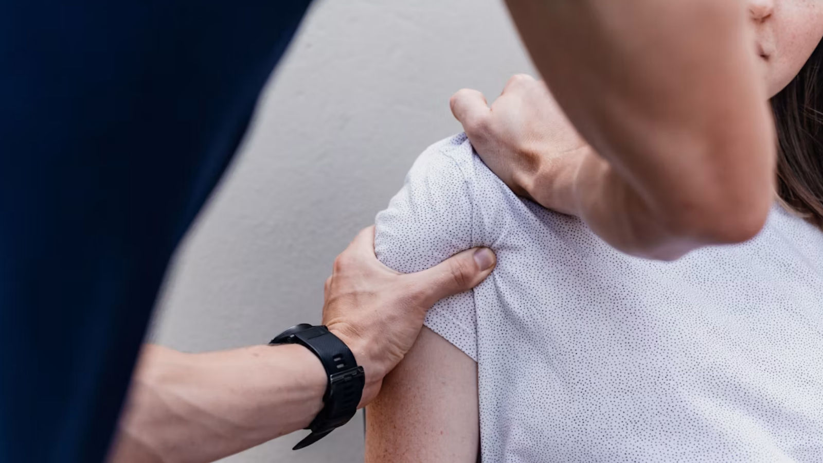 A chiropractor working on a  woman's shoulder