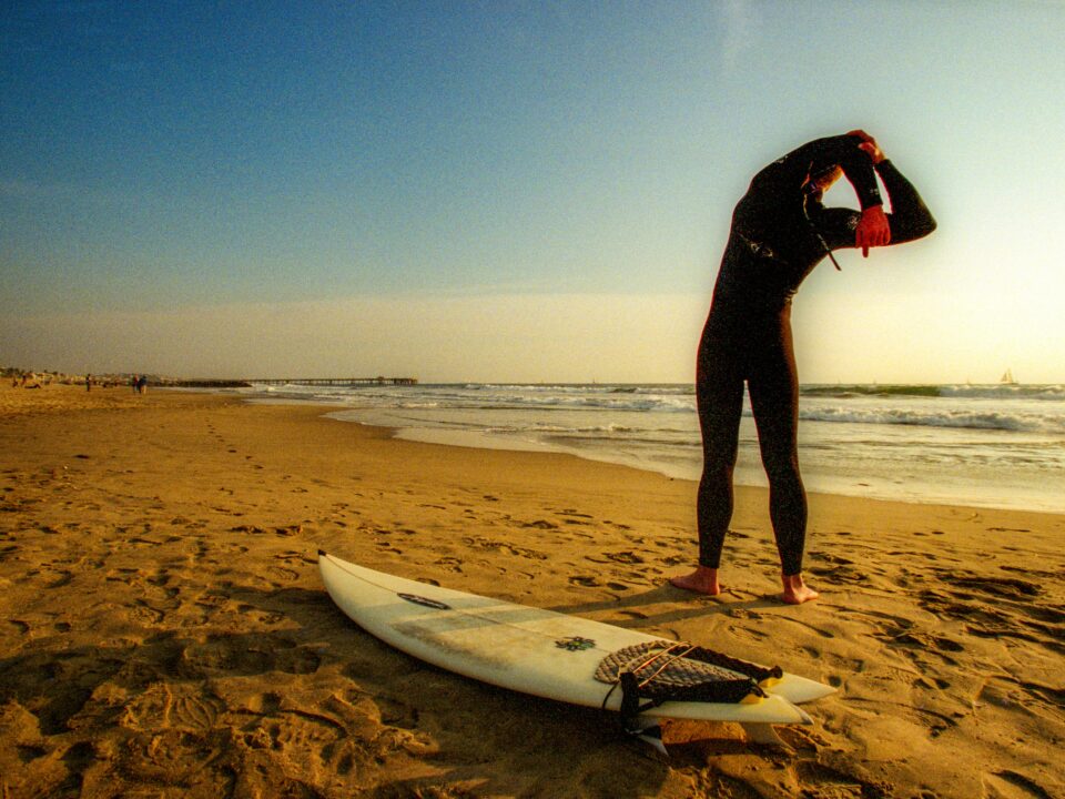 A surfer stretching on the beach
