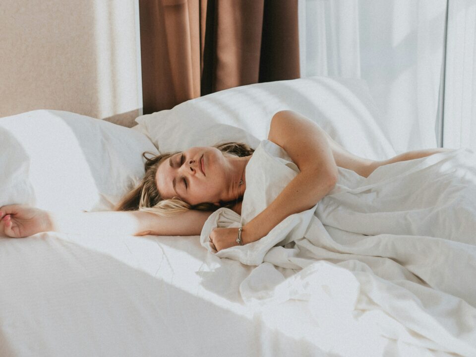 A woman sleeping soundly in a bed with white covers